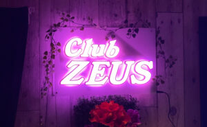 受付を終えて、入ったら左がカウンター、右は壁になっていて、そこにネオン輝く幻想的なゼウスの看板がある。